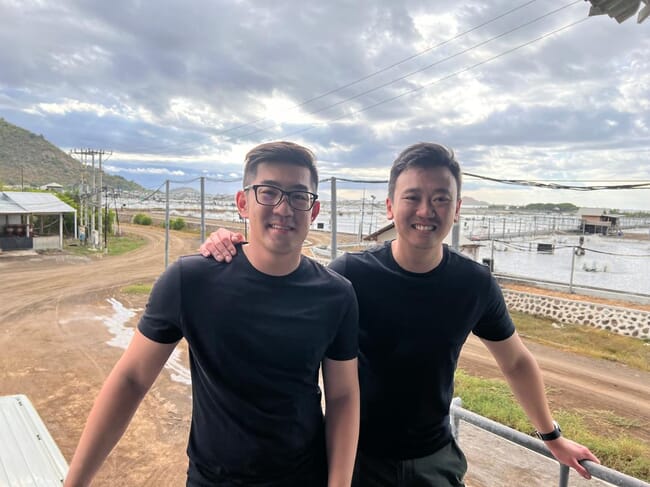 Two people beside a shrimp farm.