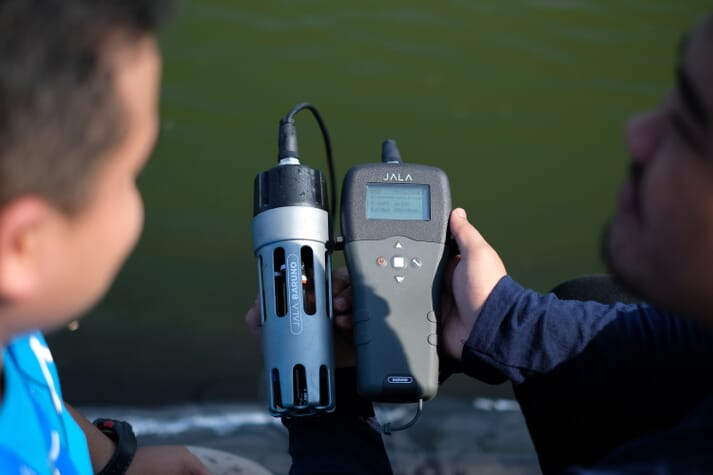 Shrimp farmer measuring water quality with JALAs AI 4-in-1 device