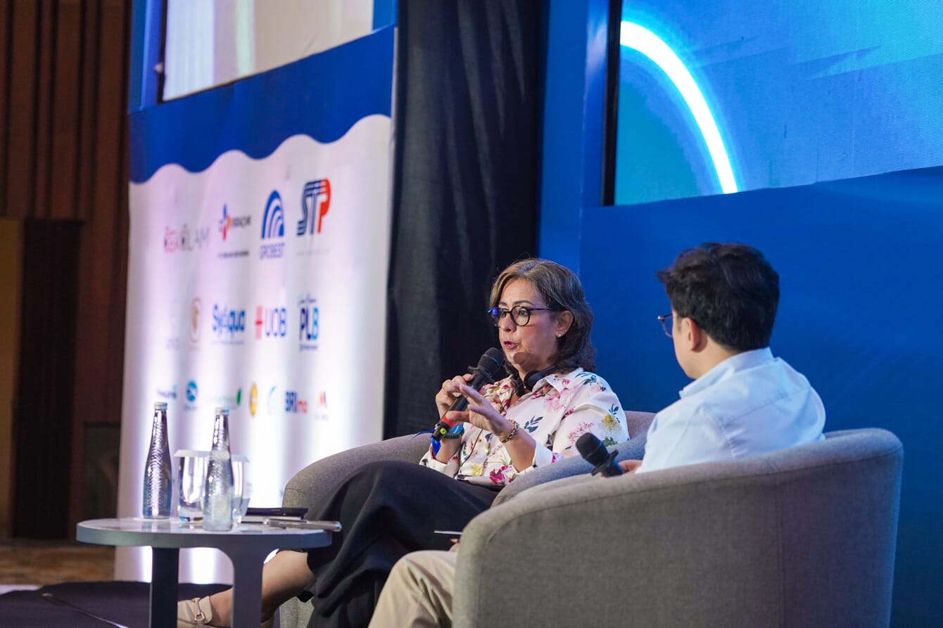 A m=woman being interviewed on stage at a conference.