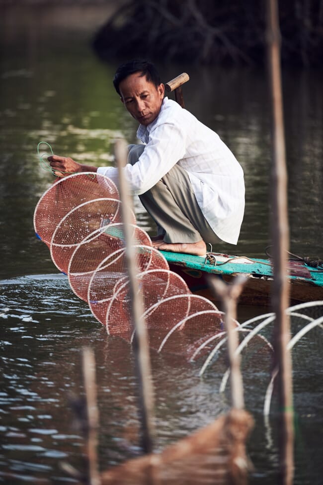 Uma pessoa armando uma rede em uma canoa escavada.