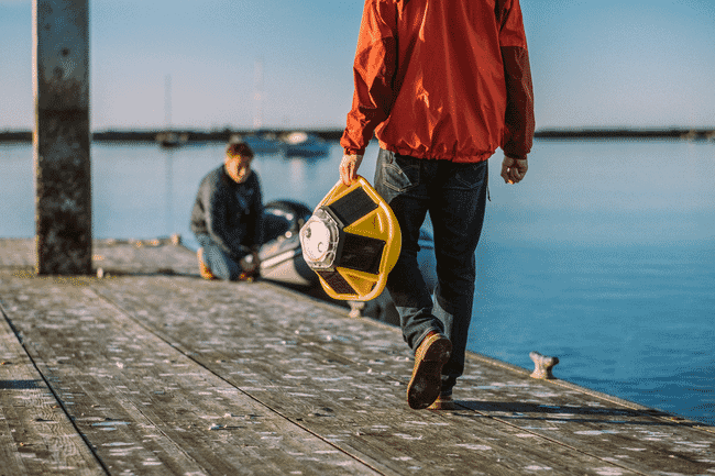 A person carrying a hi-tech buoy along a pontoon