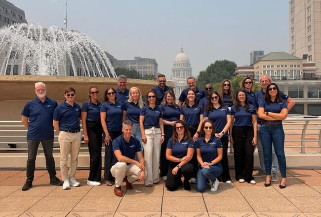 A group photo of people standing infront of a nice view.