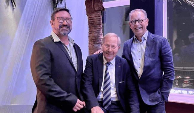 Three smiling men in suits.