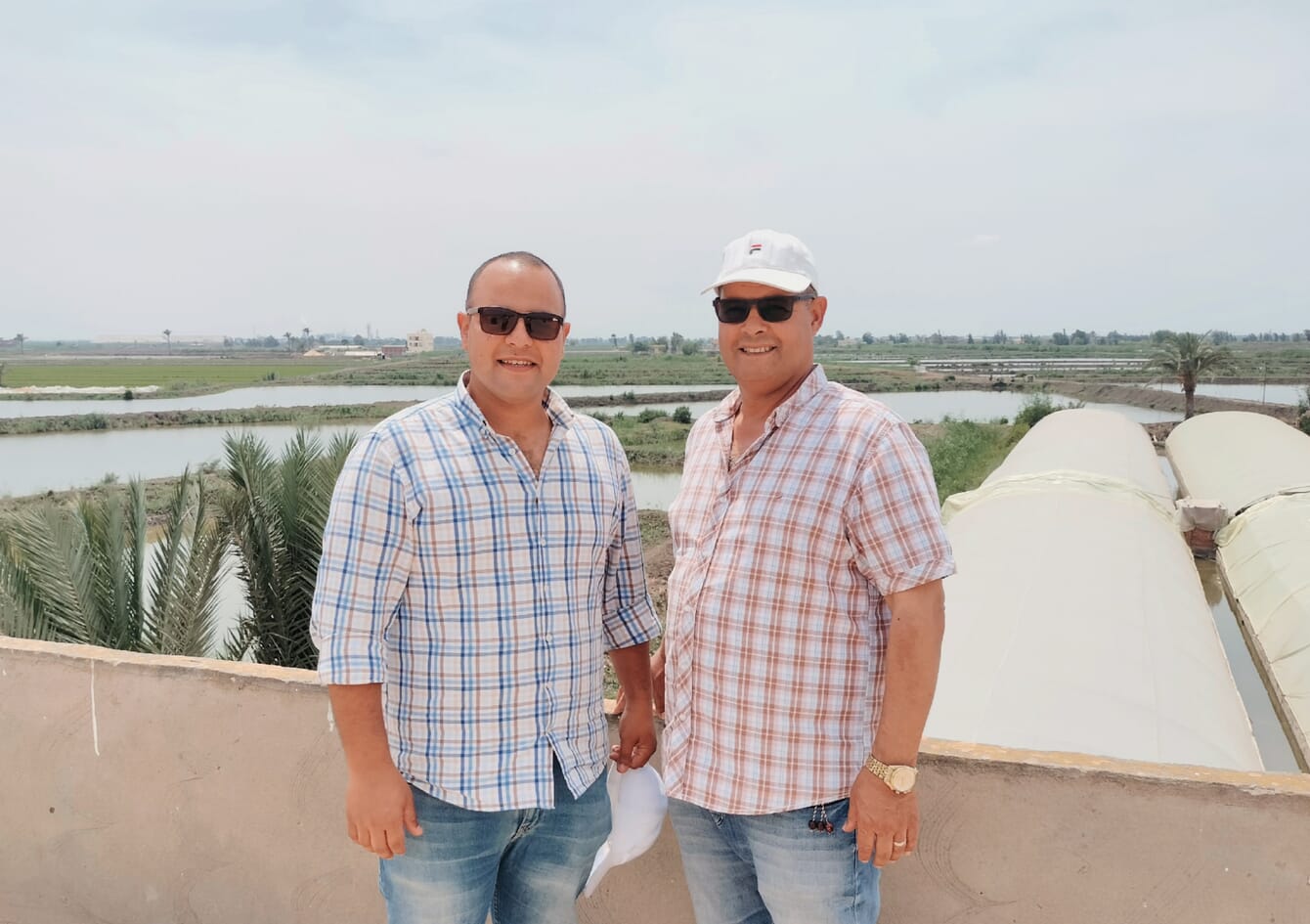 Two men standing in front of a pond.