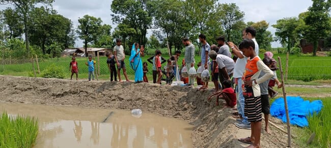 A group of people beside a pond.