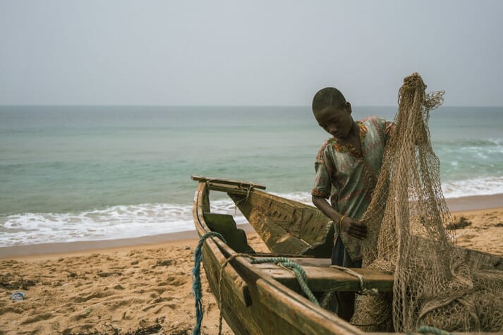 person holding a fishing net near the sea