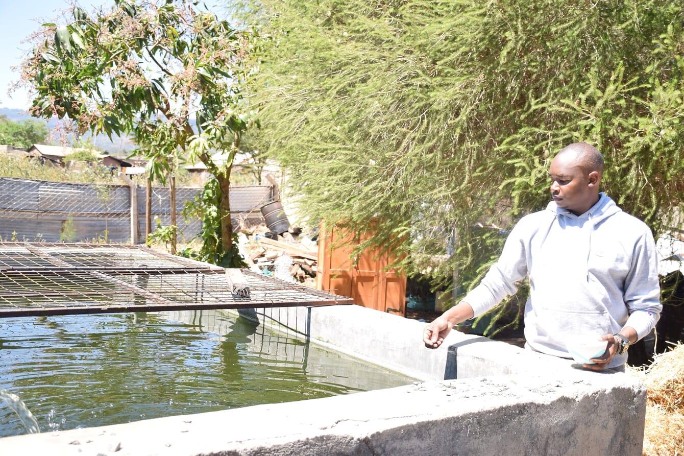 A man standing beside a concrete fish tank.