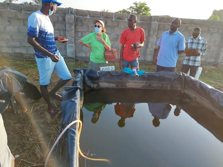 Fish farmers standing around a pond