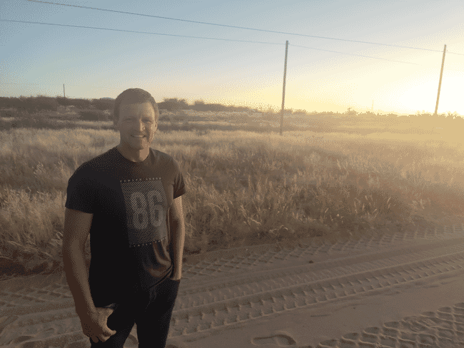 A man standing on a sand road.