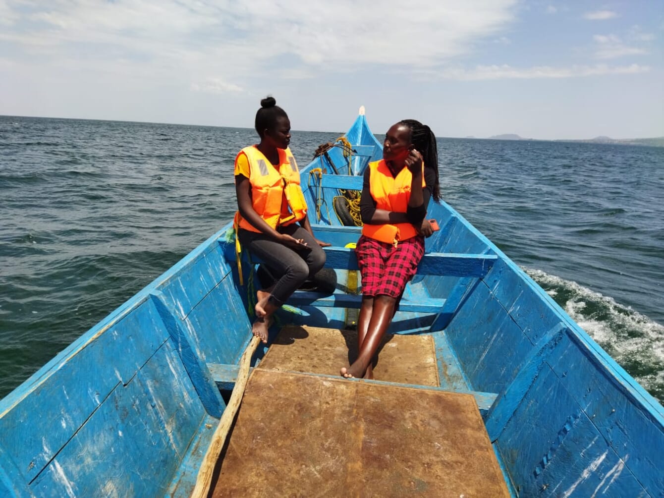 Two people in the bow of a wooden boat.