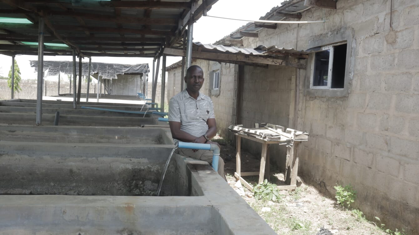 A man standing beside a series of concrete tanks.