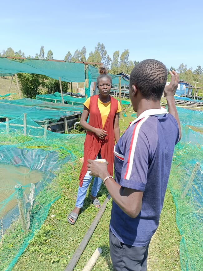 Woman talking to a man outside next to fish ponds