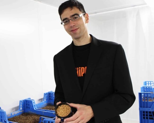 a man holding a jar of insect larvae