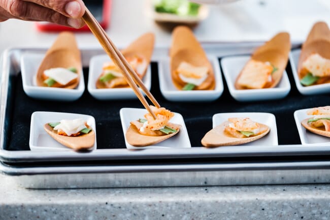 a person using chopsticks to pick up some food from a section of small plates