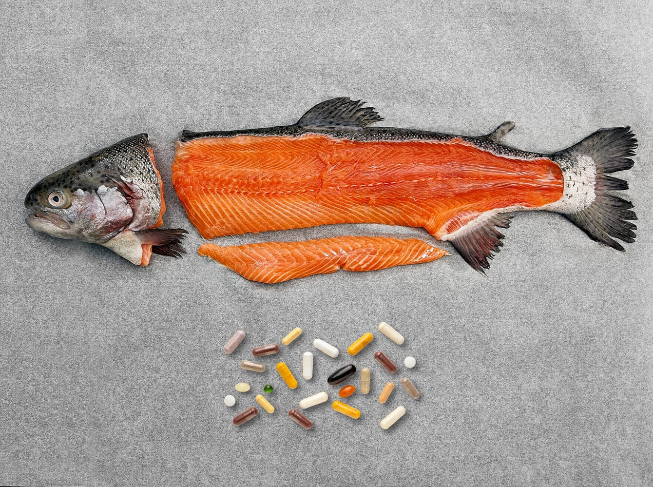 Sidestreams of Atlantic salmon next to nutitional pills.