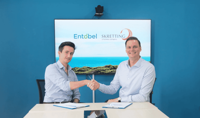 Two men shaking hands after reaching an agreement on the inclusion of insect meal in aquaculture feeds.
