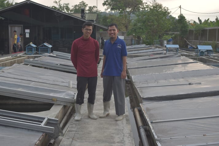 Angga Kurniawan (right) and a technician beside grow-out tanks at his eel farm