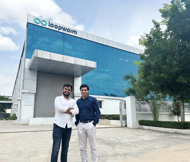 Two men standing infront of a factory.