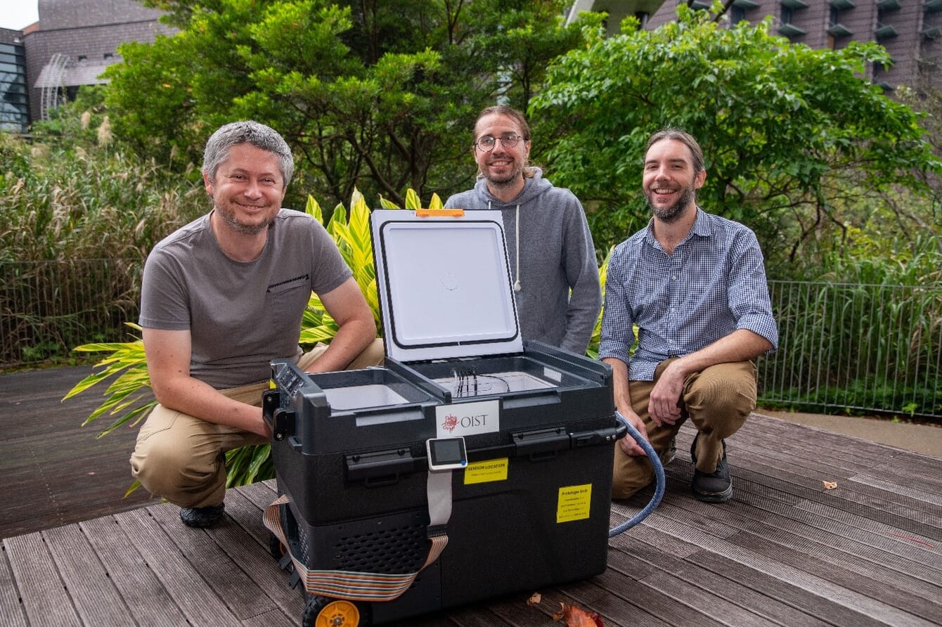 Three researchers posing infront of a machine.