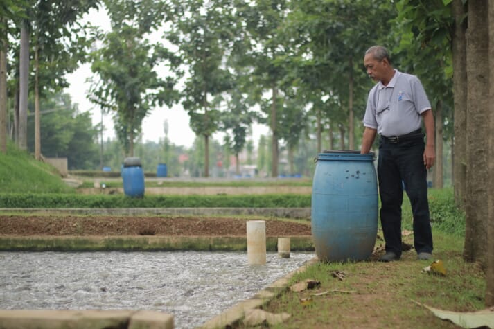 Haji Usman standing by his catfish ponds