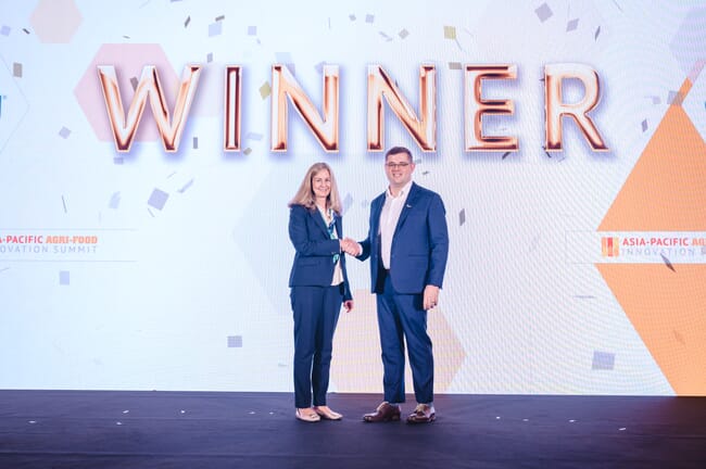 Oceanium CEO and co-founder, Karen Scofield Seal standing left on stage shaking hands with Thai Union representative in front of large sign that says "Winner".