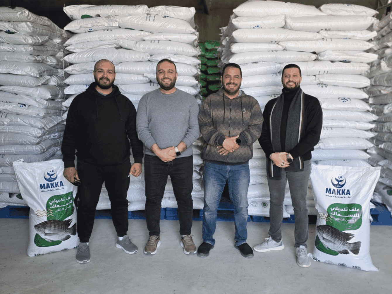 A group of four people standing infront of aquafeed bags.