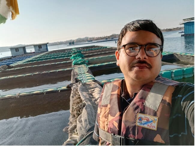 Fotografía de un hombre delante de una piscifactoría