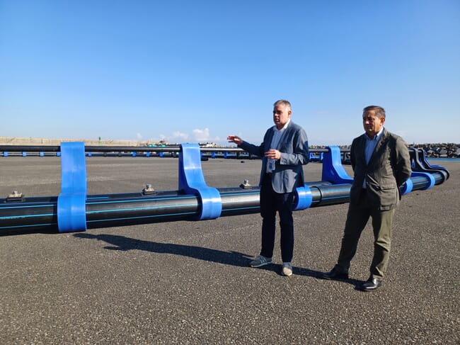 Two men standing by the aquaculture structure.