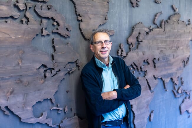 a man standing in front of a map of the world