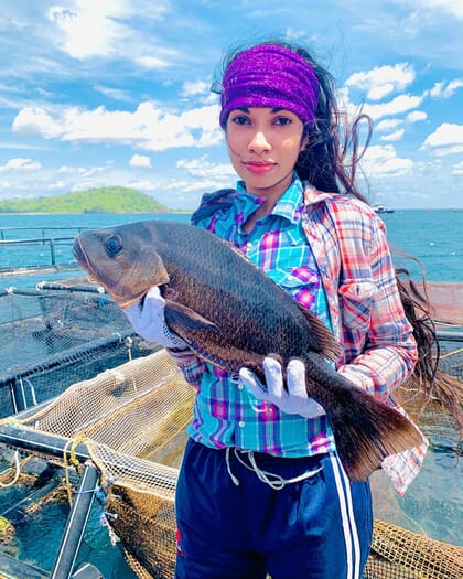 A woman holding up a fish.