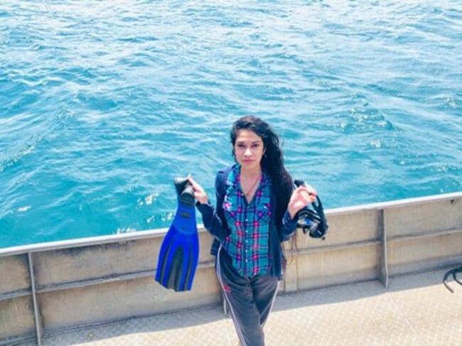 A woman holding a pair of flippers on the deck of a boat.