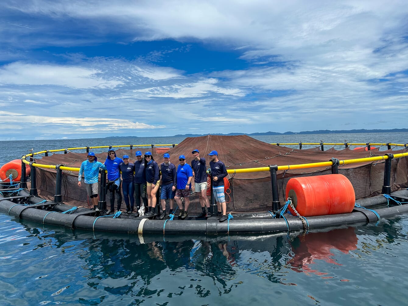 people standing on the edge of a fish pen