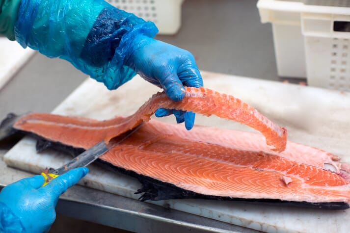 Person cutting along a side of salmon