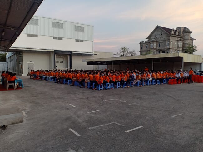 crowd sitting outside a factory