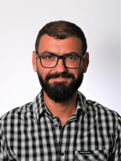 Foto da cabeça de um homem com óculos e barba
