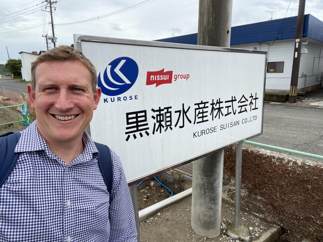 A man beside a sign with Japanese writing on it.