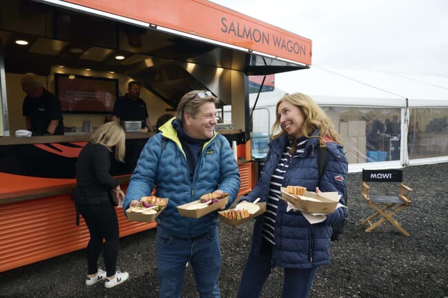 Duas pessoas segurando comida para viagem em frente a um food truck