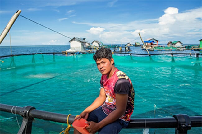 person standing on an aquaculture net pen