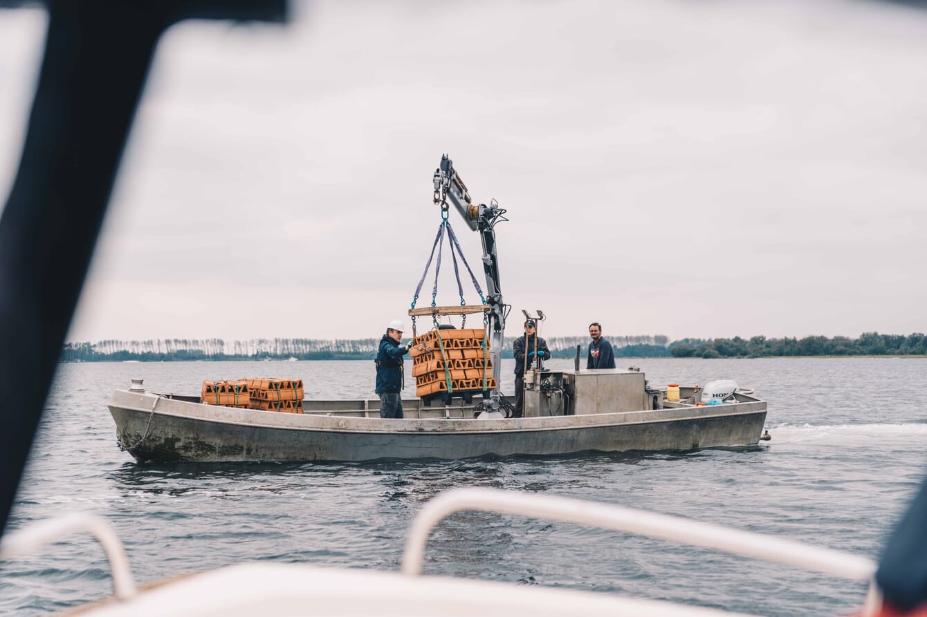 Clay bricks being lowered off the side of an inflatable boat.