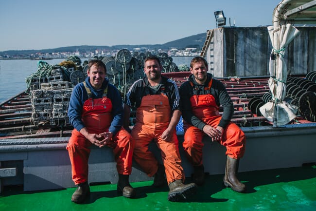 three men sitting on on the deck of a ship