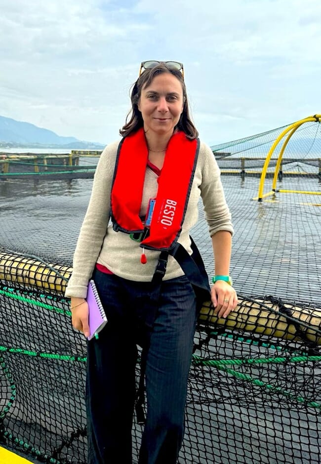 A woman standing on the edge of a fish farm pen.