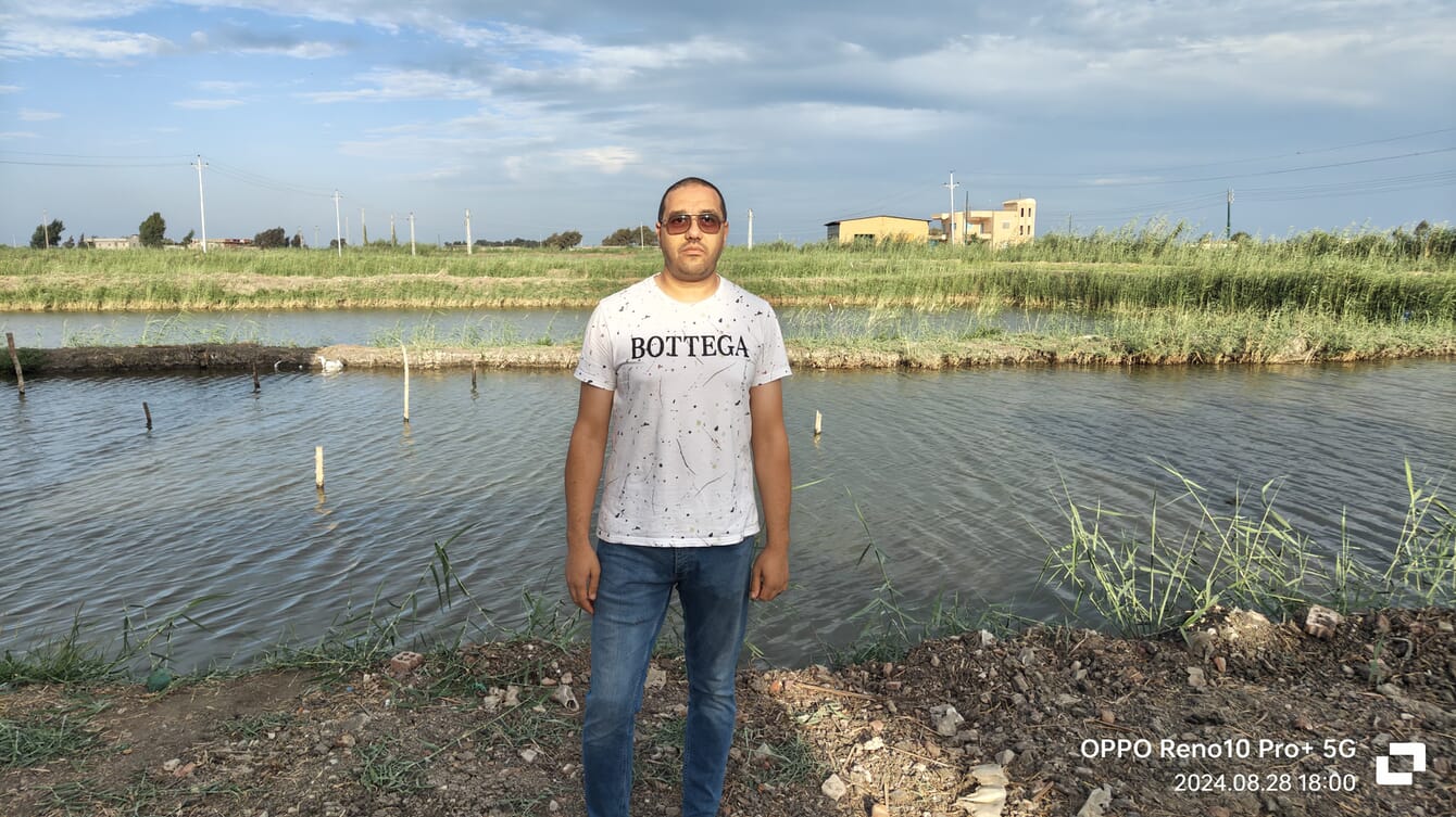 A man stands in front of his tilapia hatchery.