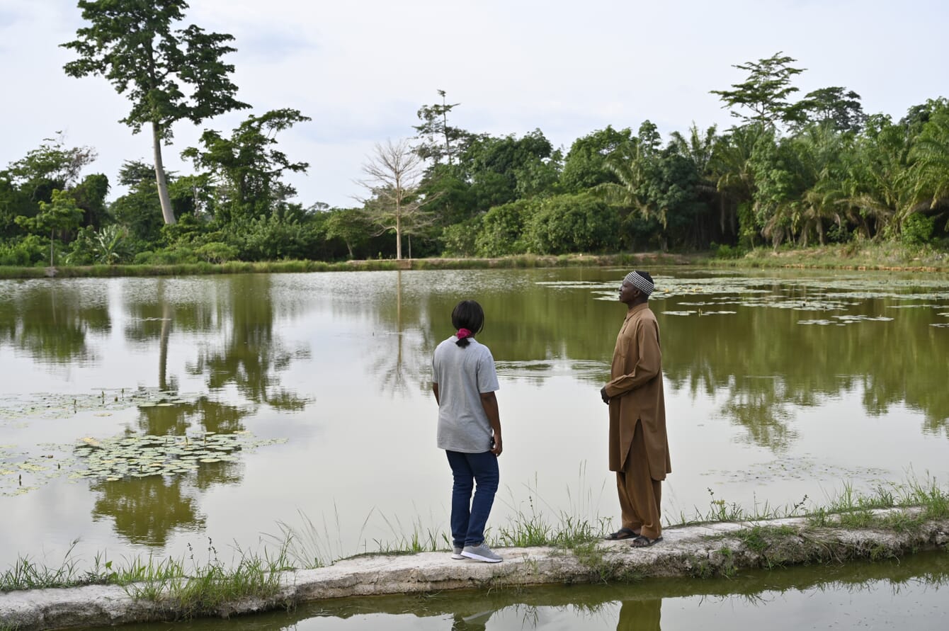 two people standing on the perimeter of a fish pond
