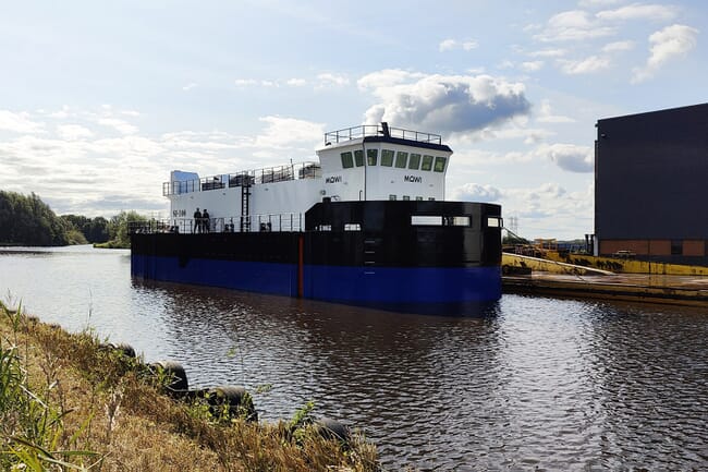 A steel feed barge being towed.