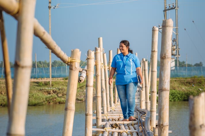 woman walking along a bamboo bridge over a pond