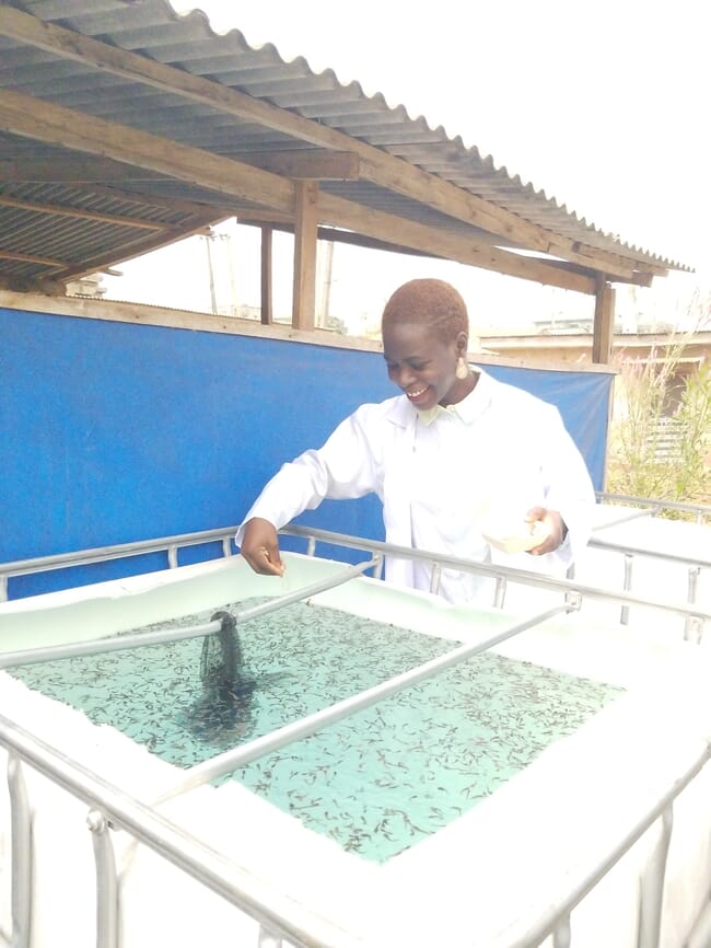 Oluwasikemi Olabisi ao lado de um tanque cheio de alevinos de bagre