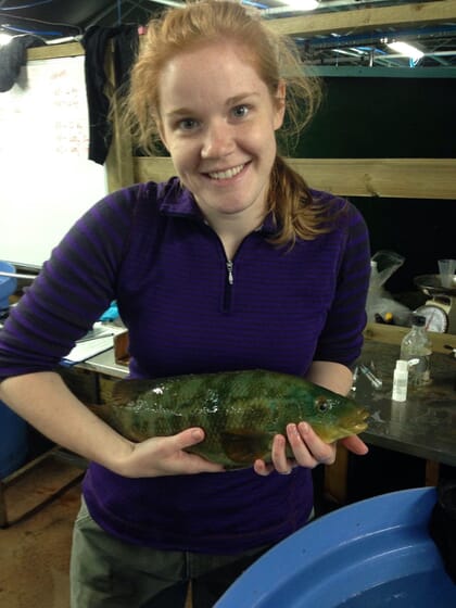 Woman holding a fish above a blue bucket