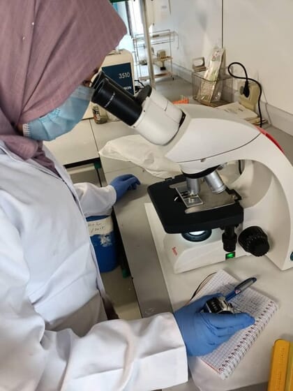 Mujer mirando por un microscopio