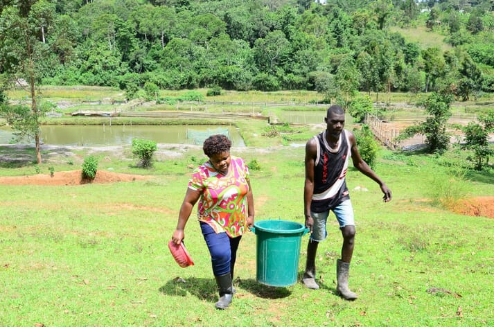 two people carrying a large bucket across a field