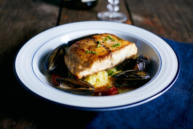 Cooked fillet of barramundi with mussels on a plate